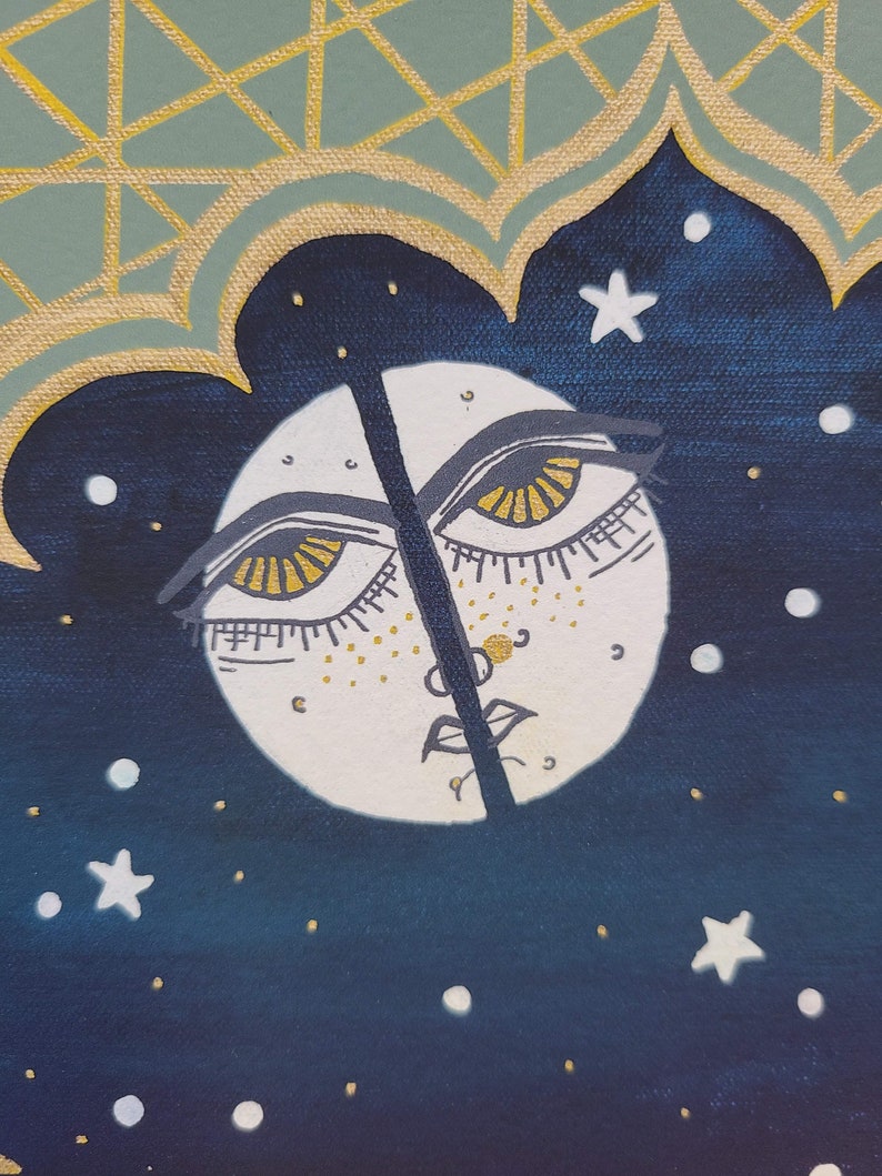 Pode incluir: Uma lua branca com um rosto e dois olhos com &iacute;ris douradas sobre um fundo azul escuro com estrelas brancas. A lua &eacute; dividida ao meio por uma linha preta.