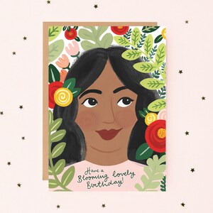 Puede incluir: Una tarjeta de cumplea&ntilde;os con una mujer de cabello negro largo rodeada de flores y vegetaci&oacute;n. El texto de la tarjeta dice "Have a Blooming Lovely Birthday!"