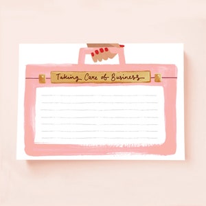 May include: Pink notepad with a hand holding a pink suitcase with a gold label that says "Taking Care of Business".