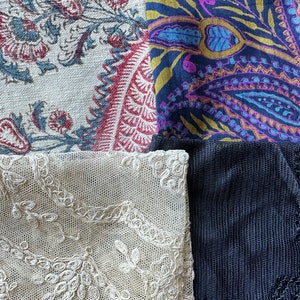 May include: A patchwork of four different fabrics. The top left fabric is a white linen with a floral pattern in shades of red, blue, and green. The top right fabric is a dark blue paisley print with gold, purple, and blue accents. The bottom left fabric is a white lace with a delicate floral pattern. The bottom right fabric is a dark blue knit fabric with a textured surface.
