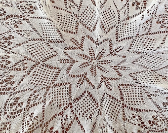 Puede incluir: Doily de ganchillo blanco con un delicado patrón floral. El doily es circular y tiene un diseño central que se asemeja a una estrella.