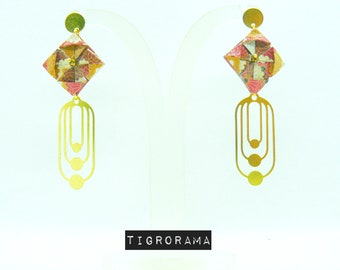 May include: A pair of gold earrings with a geometric design. The earrings feature a small, square-shaped origami flower with a pink, white, and gold pattern. The flower is attached to a long, thin gold chain with three circular links.