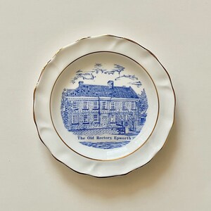 May include: A white decorative plate featuring a blue and white illustration of a building and the text "The Old Rectory Epworth." The plate has a scalloped edge and a gold rim.