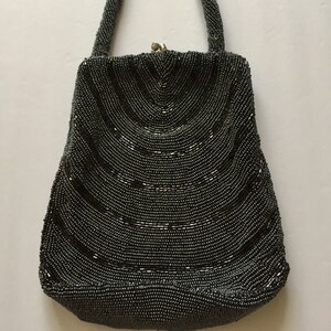 Peut inclure: Un sac &agrave; main de soir&eacute;e gris perl&eacute; avec un design incurv&eacute; et une fermeture &agrave; fermoir sur le dessus.