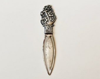 May include: Silver bookmark with an anchor and floral design. The anchor is surrounded by flowers and leaves.