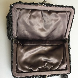 Peut inclure: Un sac &agrave; main de soir&eacute;e noir en perles avec une doublure en satin et une fermeture &agrave; fermoir. Le sac a une courte poign&eacute;e.