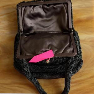 Peut inclure: Un sac &agrave; main de soir&eacute;e noir en perles avec une doublure en satin et une fermeture &agrave; fermoir sur le dessus. Le sac a une seule poign&eacute;e en perles.