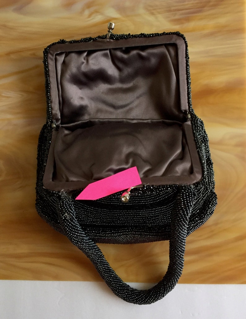 Peut inclure: Un sac &agrave; main de soir&eacute;e noir en perles avec une doublure en satin et une fermeture &agrave; fermoir sur le dessus. Le sac a une seule poign&eacute;e en perles.