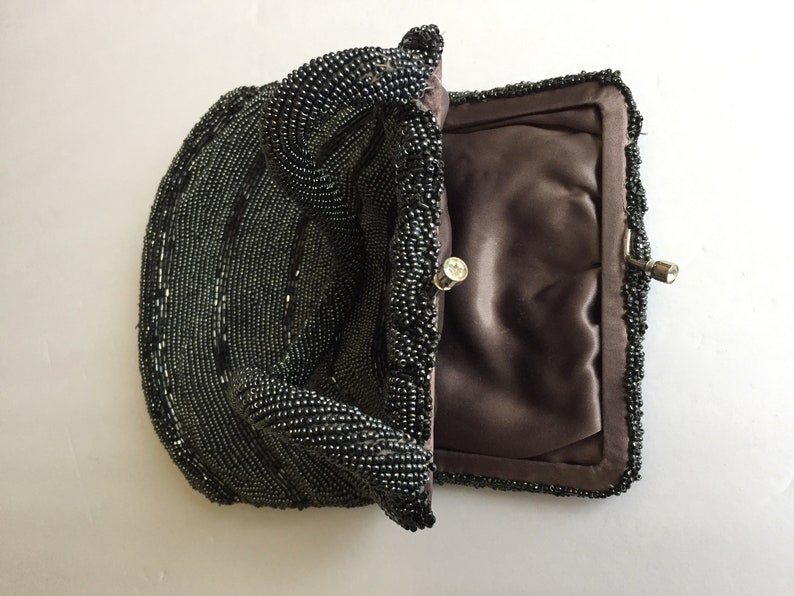 Peut inclure: Un sac &agrave; main de soir&eacute;e noir en perles avec une doublure en satin et un fermoir argent&eacute;.