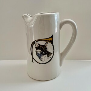 May include: White ceramic pitcher with a fox and a hunting horn design.