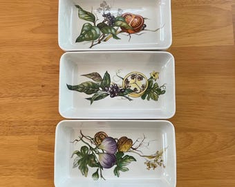 May include: Three rectangular ceramic serving dishes with botanical illustrations. Each dish features a different design of fruits and vegetables, including tomatoes, grapes, and figs, with green leaves and vines.