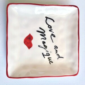 Op de afbeelding: Een handgemaakt houten bord met de tekst "Welcome" in een speels lettertype. Het wit geschilderde bord heeft een verweerde afwerking en een decoratief bloemmotief in roze en groene tinten. Het meet ongeveer 30 cm breed en 15 cm hoog.