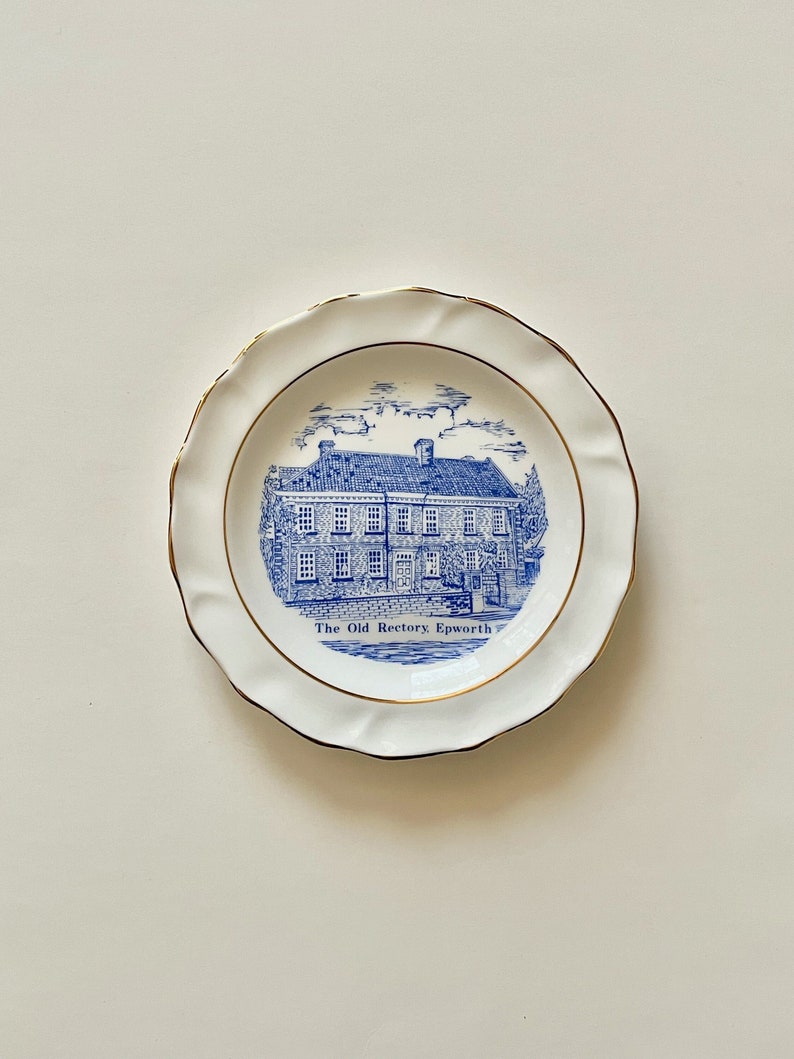 May include: A white decorative plate featuring a blue and white illustration of a building and the text "The Old Rectory Epworth." The plate has a scalloped edge and a gold rim.
