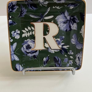 May include: Square decorative tray with a floral pattern in shades of green and blue. The tray has a gold trim and a large white letter "R" in the center. Butterflies and dragonflies are also part of the design.