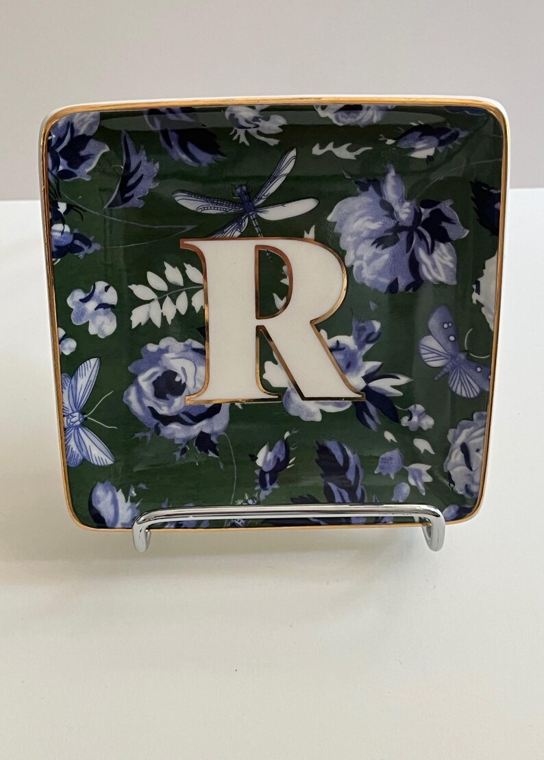 May include: Square decorative tray with a floral pattern in shades of green and blue. The tray has a gold trim and a large white letter "R" in the center. Butterflies and dragonflies are also part of the design.