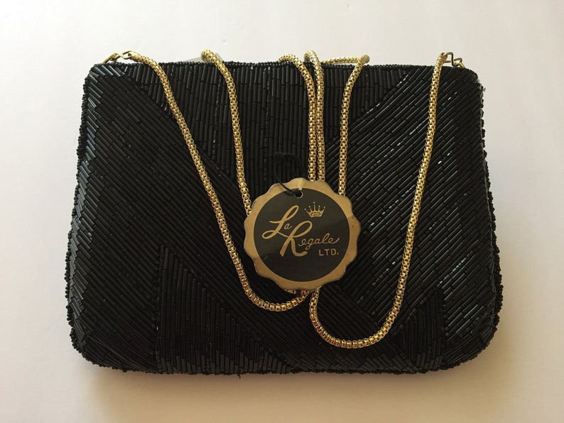 Peut inclure: Un sac &agrave; main de soir&eacute;e noir en perles avec une bandouli&egrave;re en cha&icirc;ne dor&eacute;e et une &eacute;tiquette indiquant "Le Regale LTD."
