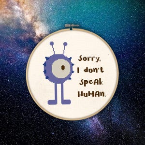 Op de afbeelding: Een paarse alien met één groot oog en drie antennes zegt "Sorry, ik spreek geen mens." in bruine tekst op een witte achtergrond.