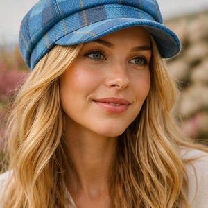 May include: A blue plaid newsboy cap with a short brim. The cap features a pattern of light and dark blue squares with thin yellow lines. The hat is made of a textured fabric.