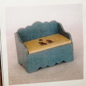May include: A blue toy box seat with a scalloped edge and a light brown lid. The lid has a painted design of two birds. The box is 2 inches tall, 2 3/8 inches wide, and 1/38 inch deep.