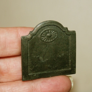 Peut inclure: Un petit écran de cheminée en métal vert foncé avec un motif décoratif en haut.