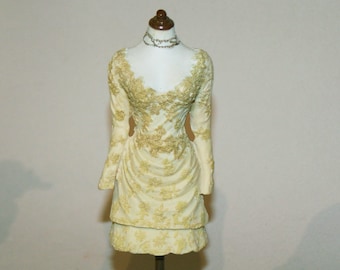 May include: A white dress with gold embroidery on a mannequin stand. The dress has a fitted bodice and a full skirt. The mannequin is wearing a gold necklace.