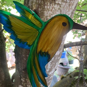 Yellow, green and blue hovering hummingbird metal wall art.