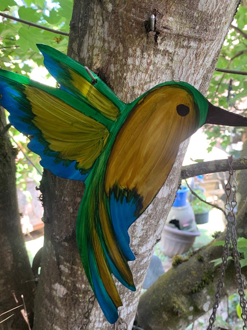 Yellow, green and blue hovering hummingbird metal wall art.