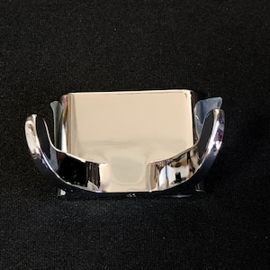 May include: Chrome-plated double hook for hanging towels or robes. The hook is mounted on a rectangular base.