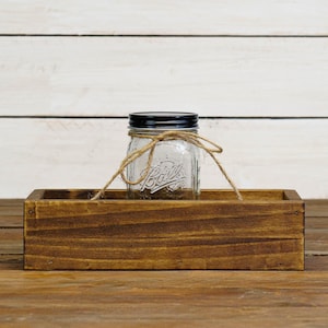 May include: A rustic wooden box with a clear glass jar with a black lid and twine tied around it. The jar has the word "Ball" embossed on it.