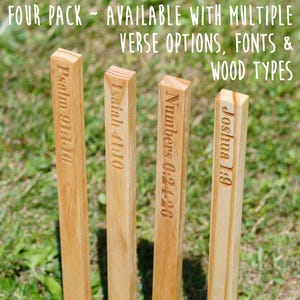 Peut inclure: Quatre piquets en bois avec des versets bibliques gravés : Psaume 91:1-10, Ésaïe 41:10, Nombres 6:24-26 et Josué 1:9. Le texte "FOUR PACK - AVAILABLE WITH MULTIPLE VERSE OPTIONS, FONTS & WOOD TYPES" est en haut. Les piquets sont marron clair.