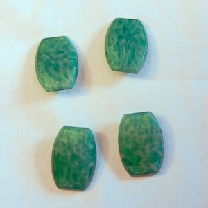 May include: Four green oval-shaped beads with a marbled pattern. The beads are made of a translucent material and have a light green color.