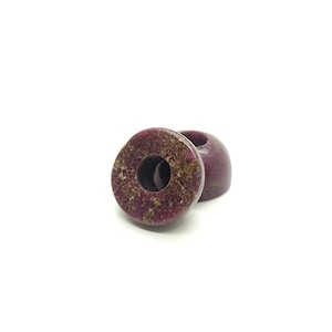 May include: Two purple and gold donut-shaped beads with a hole in the center.