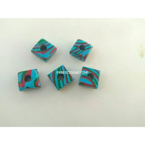 May include: Five square-shaped beads with a hole in the centre. The beads are made of a blue, green, and red stone with a swirling pattern.