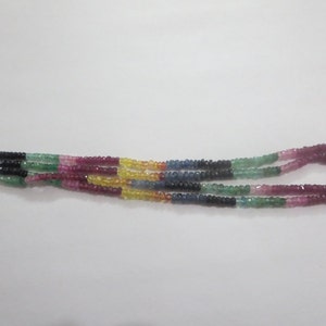 Pode incluir: Um colar de várias voltas composto por pequenas contas facetadas em uma variedade de cores, incluindo azul, verde, rosa, amarelo e vermelho. As contas são enfiadas para criar um efeito em camadas, adequado para joias.