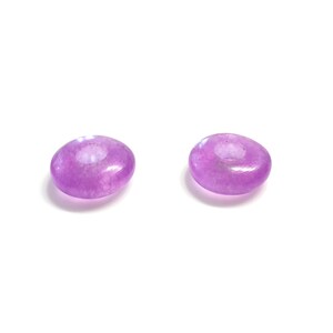 May include: Two purple donut-shaped beads with a hole in the center. The beads are made of a translucent material and have a slightly iridescent finish.