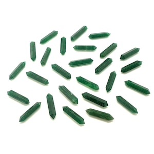 Op de afbeelding: Een verzameling groene kwartskristalpunten, elk met een dubbele punt. De kristallen zijn verspreid op een witte achtergrond, waarbij hun facetten en verschillende afmetingen worden benadrukt. De kristallen hebben een doorschijnend uiterlijk.
