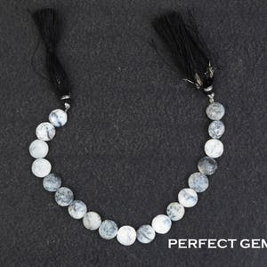 May include: A strand of round, white and gray gemstone beads with black tassels at each end. The beads have a speckled pattern. The text "PERFECT GEMSTONE" is visible at the bottom right.