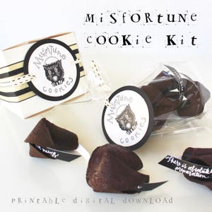 May include: Printable digital download for a Misfortune Cookie Kit. The kit includes a black and white illustration of a cat with the text "Misfortune Cookies" on a white circle. The image also shows a clear plastic bag with chocolate fortune cookies inside.