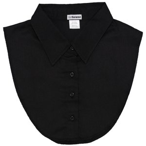Puede incluir: Un cuello de camisa negro desmontable con botones. El cuello tiene un diseño clásico puntiagudo y está hecho de una tela lisa. La etiqueta dice "Got Collared".