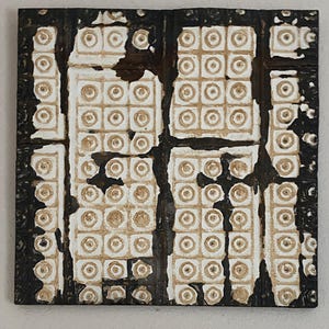 May include: A square ceramic tile with a black border and a white background. The tile is decorated with a pattern of small circles arranged in a grid.