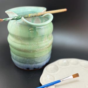 May include: A set of three ceramic mugs with a speckled, matte finish. The mugs are in shades of cream, light brown, and dark brown. Each mug has a simple, minimalist design, perfect for coffee or tea.