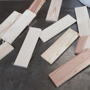 May include: A collection of wooden craft sticks, some are natural wood color and some are stained a light brown color.