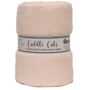May include: A roll of soft, light beige fabric labeled "Cuddle Cuts." The fabric is 3 yards of precut, extra-wide material. The label is white with black text and a black border. The fabric appears plush and cozy.