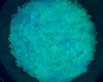 May include: A close-up of a pile of teal and blue glow-in-the-dark crystals.