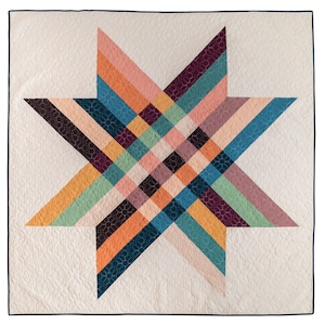 May include: A white quilt with a large, multi-colored star design. The star is made up of various shades of pink, orange, yellow, green, blue, and purple. The star is centered on the quilt and is surrounded by a white background.