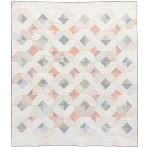 May include: A white quilt with a geometric pattern of pink, gray, and beige diamonds. The quilt is made of fabric squares sewn together to create a repeating pattern.