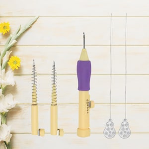 Pode incluir: Um conjunto de ferramentas de bordado com agulha de perfuração. O conjunto inclui uma agulha de perfuração com punho roxo, duas agulhas de mola e duas agulhas com pontas decorativas. As ferramentas são creme e amarelo com agulhas prateadas.