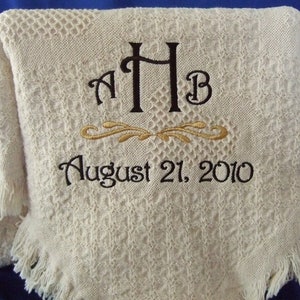 May include: A white crocheted throw blanket with a black embroidered monogram "AHB" and the date "August 21, 2010".