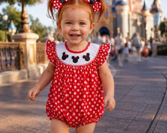 May include: A red and white polka dot bubble romper featuring a white yoke with three black mouse ear silhouettes. The outfit includes two red and white polka dot hair bows with small black mouse ears attached to each side of the hair.