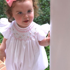 May include: A white ceramic mug with a black handle and the text "But First, Coffee" in a handwritten style. The mug is on a white surface. The mug is approximately 4 inches tall.